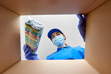 Image showing woman in mask packing kitchen sponges to box