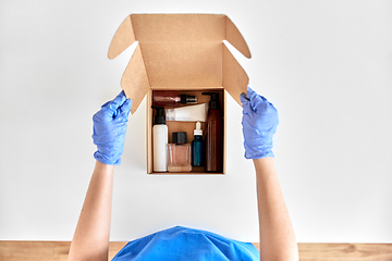 Image showing hands in gloves packing parcel box with cosmetics