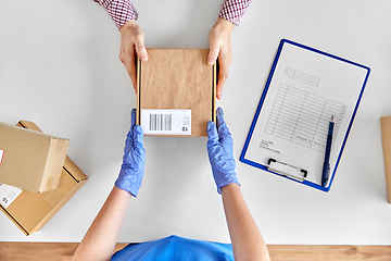 Image showing hands in gloves giving parcel box to customer