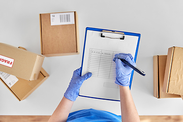 Image showing hands in gloves with clipboard and parcel boxes