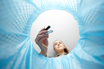 Image showing woman throwing alkaline batteries into trash can