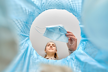 Image showing woman throwing used medical mask into trash can