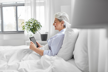 Image showing senior woman with tablet pc in bed at home bedroom