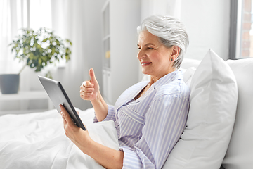 Image showing old woman with tablet pc having video call in bed