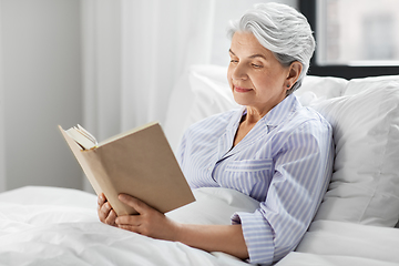 Image showing senior woman reading book in bed at home bedroom