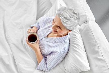 Image showing old woman with cup of coffee in bed at home