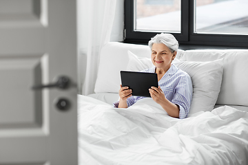 Image showing happy senior woman with tablet pc in bed at home