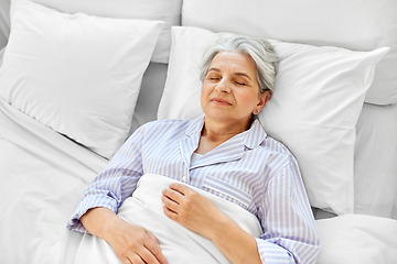 Image showing happy senior woman sleeping in bed at home bedroom