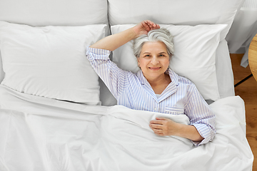 Image showing smiling senior woman lying in bed at home bedroom