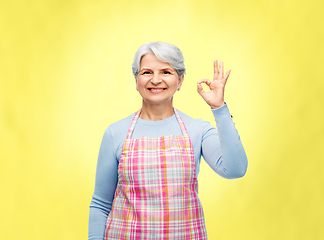 Image showing smiling senior woman in apron showing ok gesture