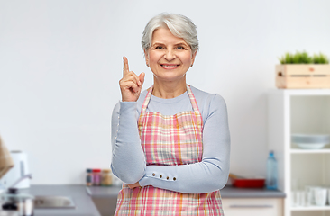 Image showing smiling senior woman pointing finger up at kitchen