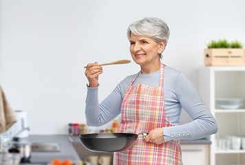 Image showing smiling senior woman with frying pan at kitchen