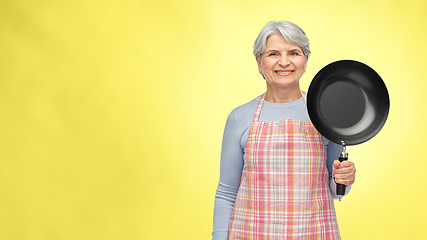 Image showing smiling senior woman in apron with frying pan