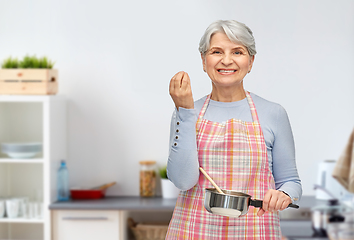 Image showing senior woman with pot cooking food at kitchen