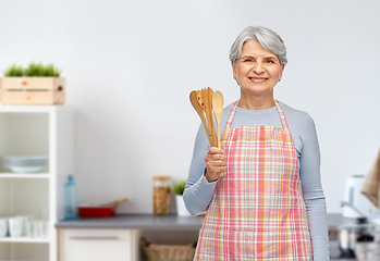 Image showing smiling senior woman with wooden spoons at kitchen