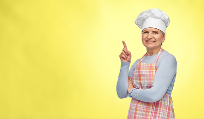 Image showing smiling senior woman or chef pointing finger up