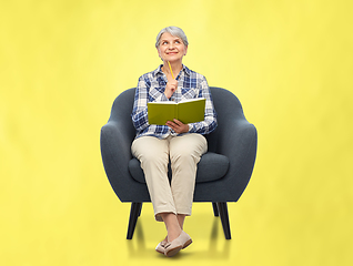 Image showing smiling senior woman in armchair writing to diary