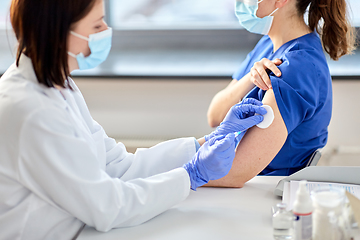 Image showing doctor with syringe vaccinating medical worker