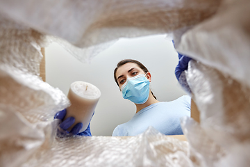 Image showing woman in mask packing candles into parcel box