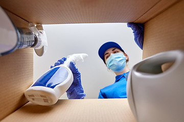 Image showing woman in mask packing cleaning supplies in box
