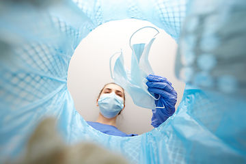 Image showing doctor throwing used medical mask into trash can