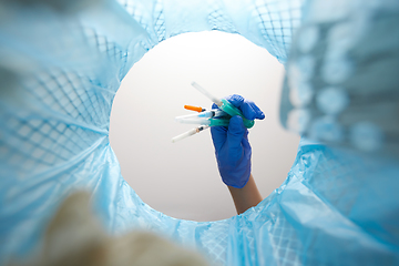 Image showing hand throwing used syringes into trash can