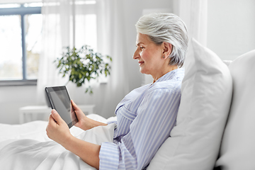 Image showing senior woman with tablet pc in bed at home bedroom