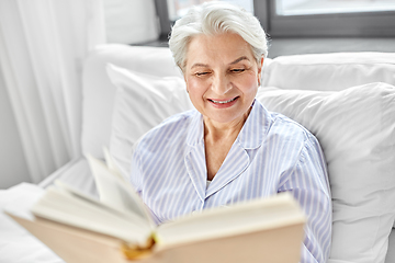 Image showing senior woman reading book in bed at home bedroom