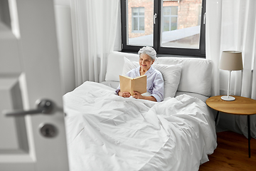 Image showing senior woman reading book in bed at home bedroom