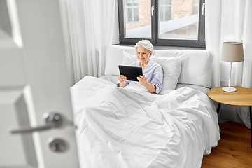 Image showing senior woman with tablet pc in bed at home bedroom