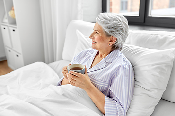 Image showing old woman with cup of coffee in bed at home