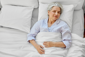 Image showing happy senior woman sleeping in bed at home bedroom