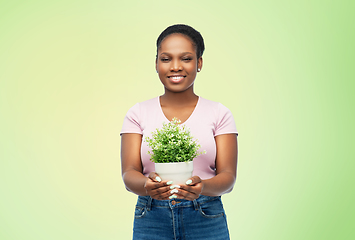 Image showing happy smiling african woman holding flower in pot