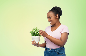 Image showing happy smiling african woman holding flower in pot