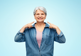 Image showing smiling senior woman showing to her face