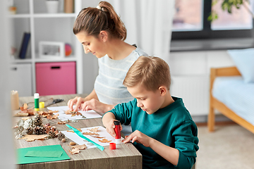 Image showing mother and son making pictures of autumn leaves