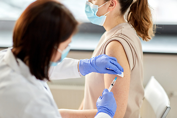 Image showing female doctor with syringe vaccinating patient