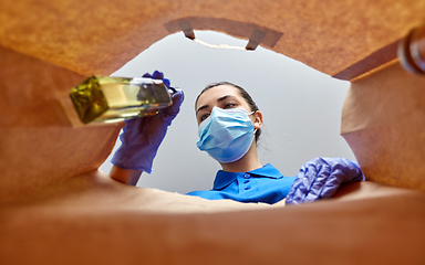 Image showing woman in gloves and mask with food in paper bag