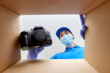 Image showing woman in mask packing camera into parcel box