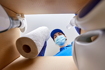 Image showing woman in mask packing cleaning supplies in box