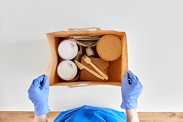 Image showing delivery woman in gloves packing food and drinks