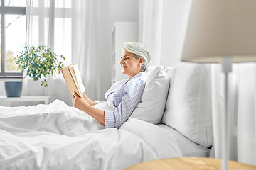 Image showing senior woman reading book in bed at home bedroom