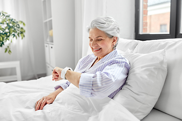 Image showing happy senior woman sitting in bed at home bedroom