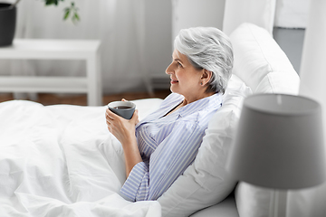 Image showing old woman with cup of coffee in bed at home