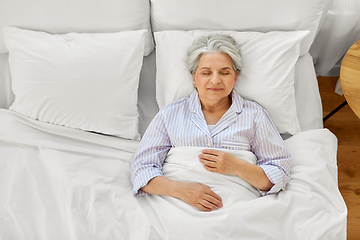 Image showing happy senior woman sleeping in bed at home bedroom