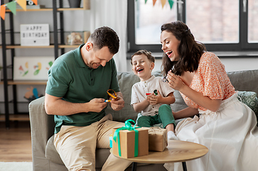 Image showing happy family with gifts and party blowers at home