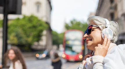 Image showing old woman in headphones listens to music in london