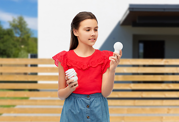 Image showing smiling girl comparing different light bulbs