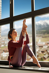 Image showing woman doing yoga exercise on window sill at studio