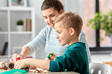 Image showing mother and son making pictures of autumn leaves